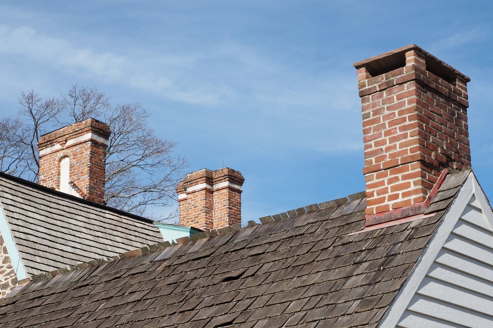 Old red brick chimneys rising above a weathered shingle roof