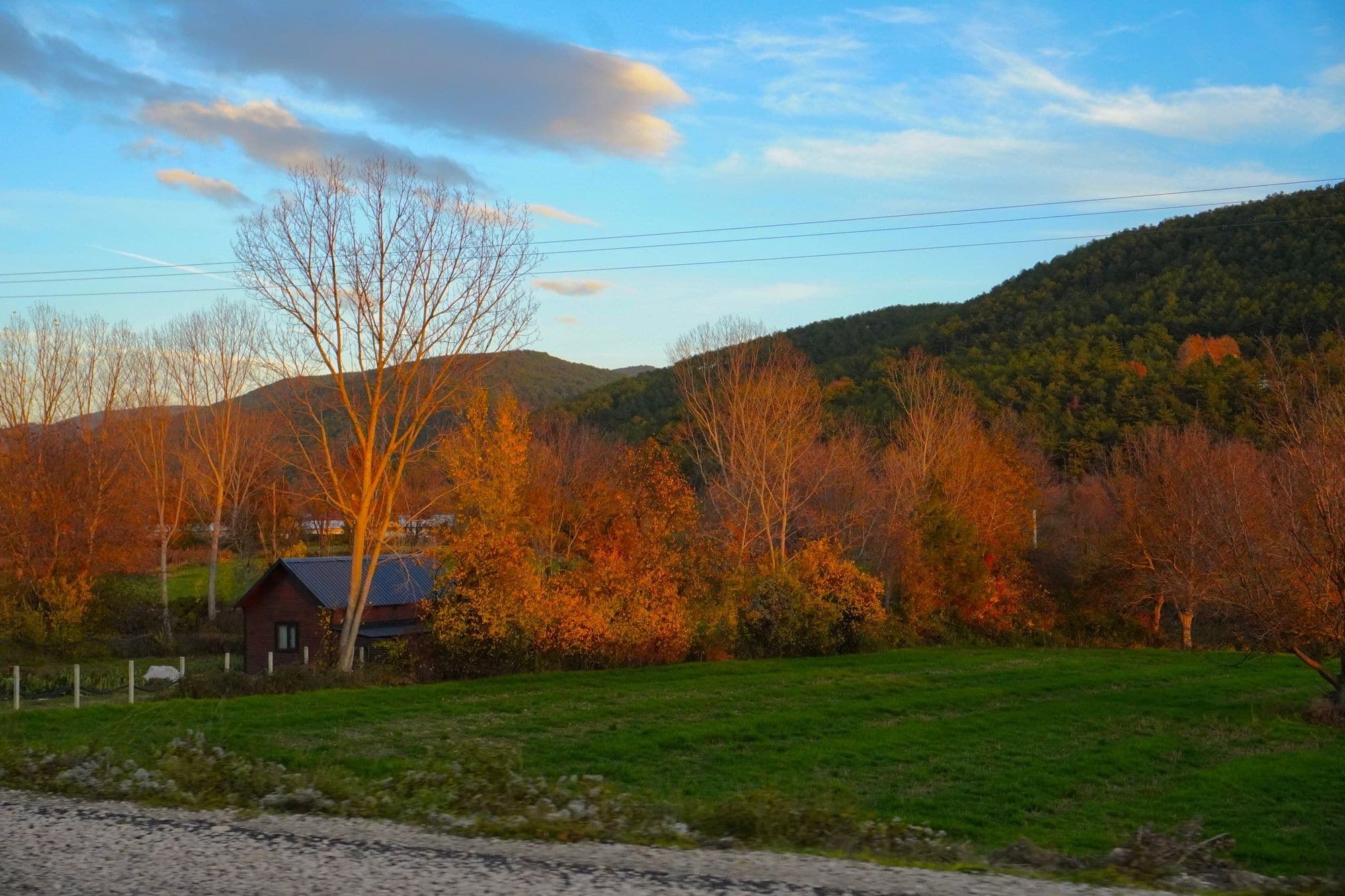 Small house below wooded hills in autumn color